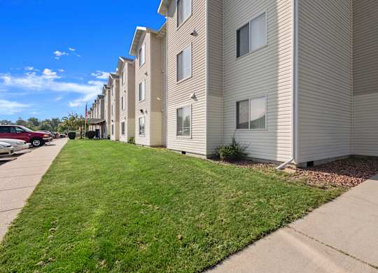 A row of apartment buildings with a grassy area in front.
