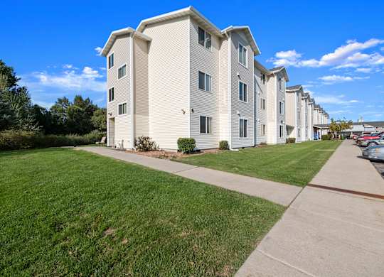 A row of apartment buildings with a sidewalk in front.