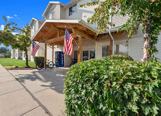 A building with a porch and American flags hanging from it.