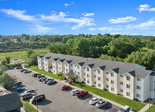 A parking lot in front of a white apartment building.