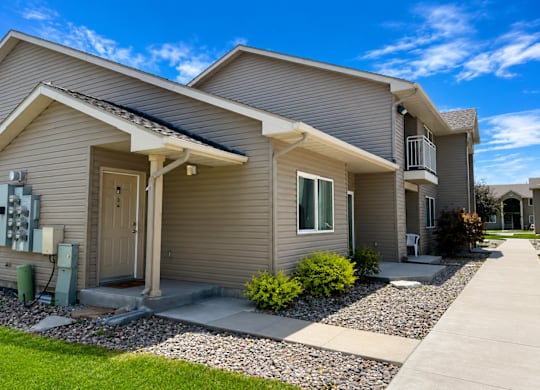 A house with a grey siding and a brown door is shown.