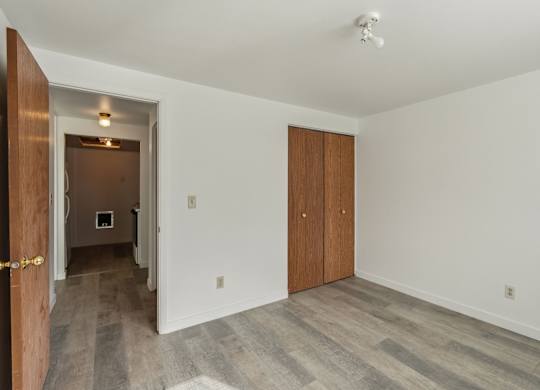 A room with a wooden door and a white wall.