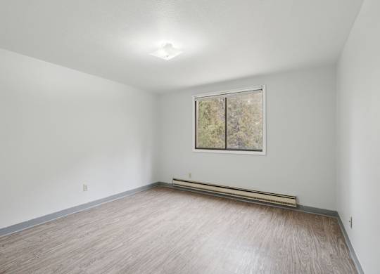 A room with a window and a painting on the wall.