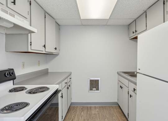 A kitchen with white cabinets and a stove top oven.
