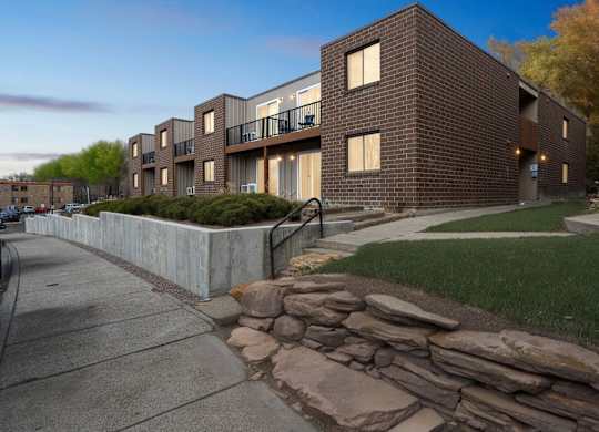 A modern brick building with a stone wall in front.