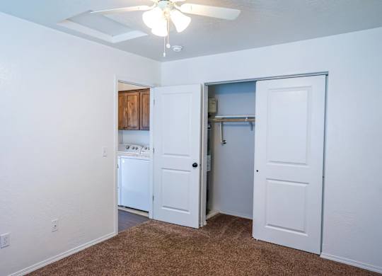 A room with a brown carpet and a ceiling fan.