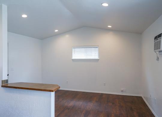 A room with a window and a wooden floor.
