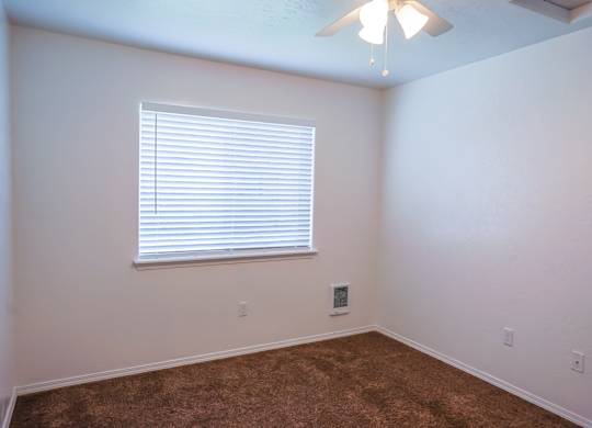 A room with a window and a ceiling fan.