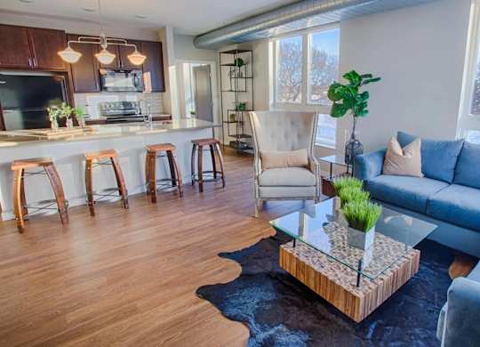 A living room with a blue couch and a glass coffee table.