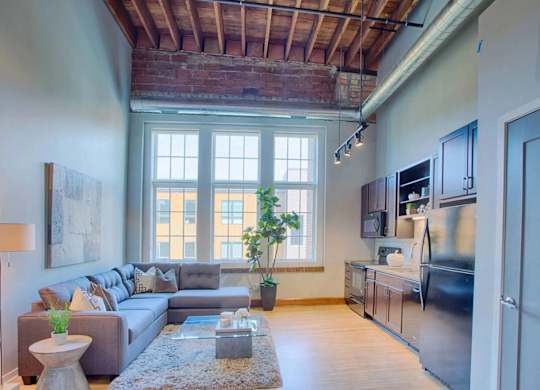 A living room with a grey couch and a large window.