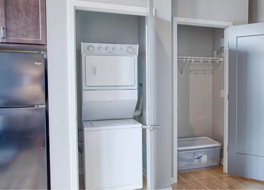 A small kitchen with a refrigerator, a sink, and a small white bathtub.