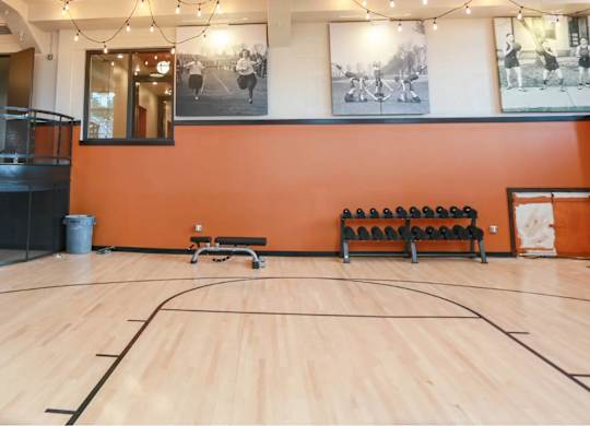 A basketball court with a wooden floor and a basketball hoop.