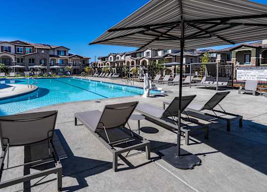 A poolside area with sun loungers and a shade umbrella.