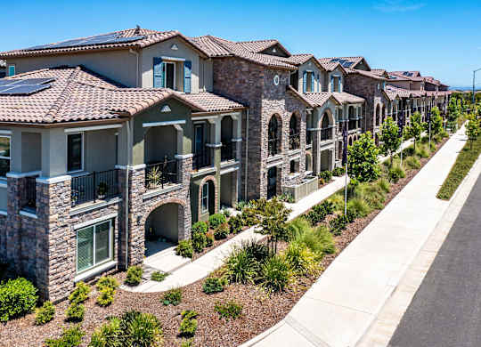 A row of houses with a sidewalk in front.