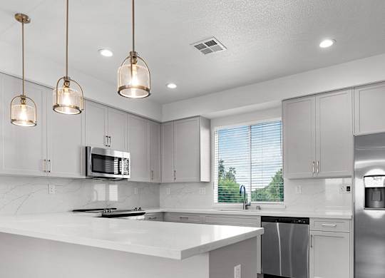 a white kitchen with stainless steel appliances and white counter tops