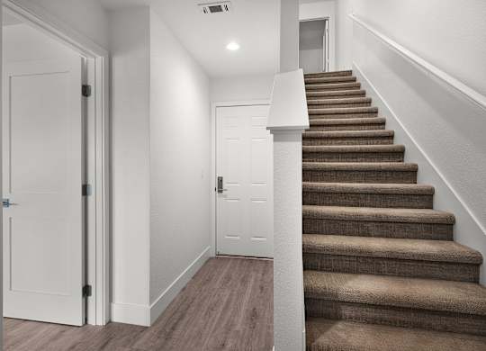 a staircase in a home with white walls and wood treads