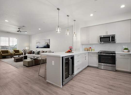 an open kitchen and living room with white cabinets and a counter top