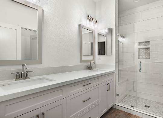 a white bathroom with two sinks and a shower