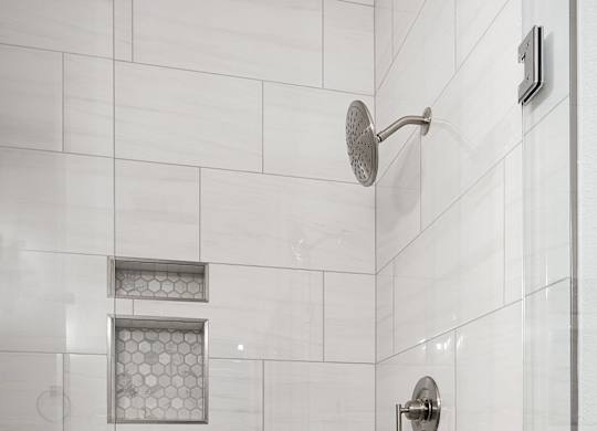 a large shower with white tiles in a bathroom