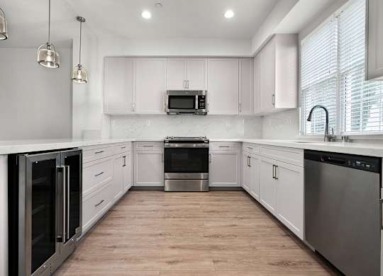 an all white kitchen with stainless steel appliances and white cabinets