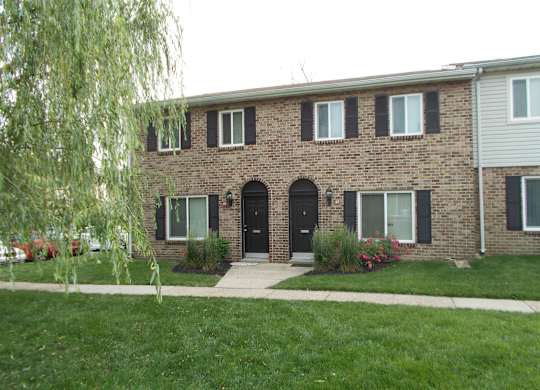 A brick house with a black front door and windows.