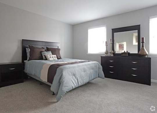 A bedroom with a bed, dresser, and mirror.