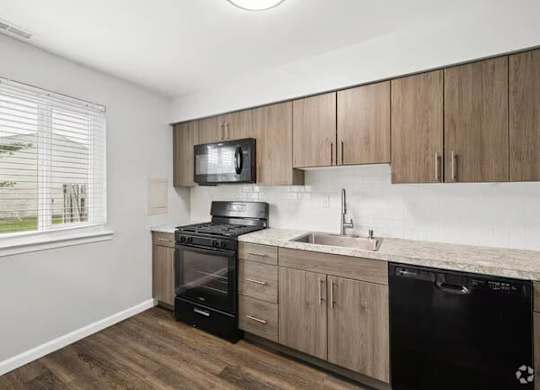 A kitchen with wooden cabinets and black appliances.