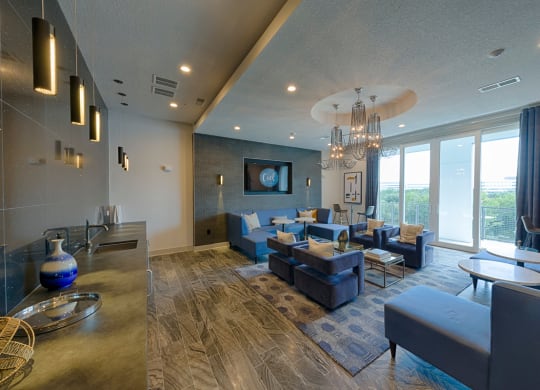 Open concept living room with modern kitchen and blue furniture at Ciel Luxury Apartments, Florida