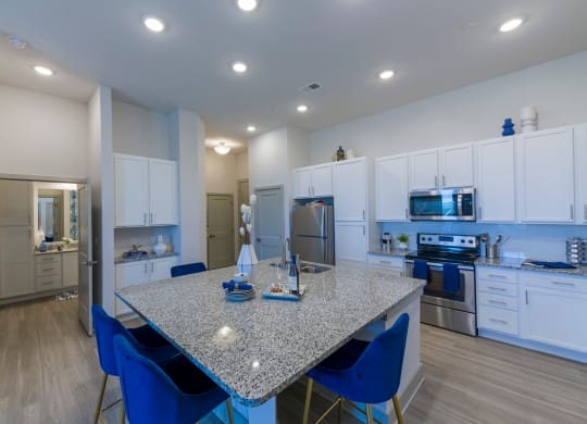 Modern kitchen with granite island and blue bar stools at Ciel Luxury Apartments, Jacksonville, FL