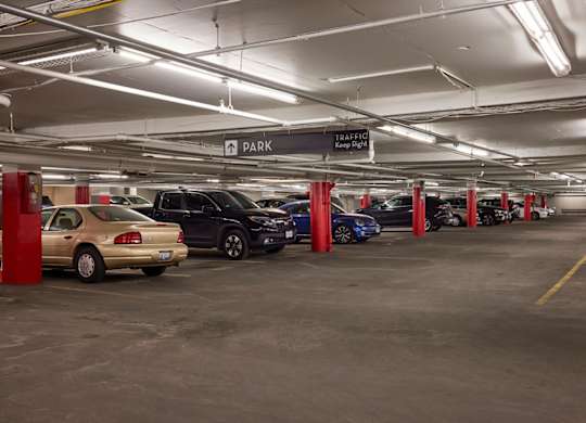 A parking garage with cars parked in red pillars.