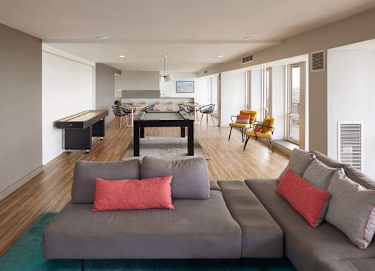 A living room with a grey couch and a green rug.