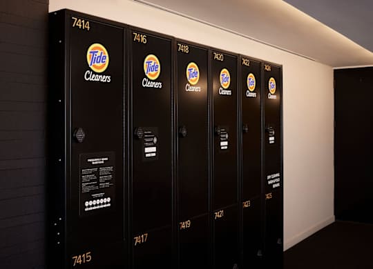 A row of Tide cleaners are lined up against a wall.