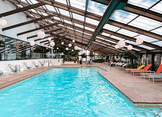 A large indoor swimming pool with sun loungers and a glass ceiling.