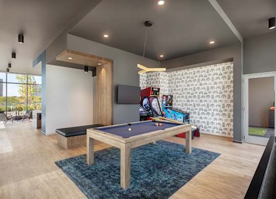 A pool table in a room with a TV and a patterned wallpaper.