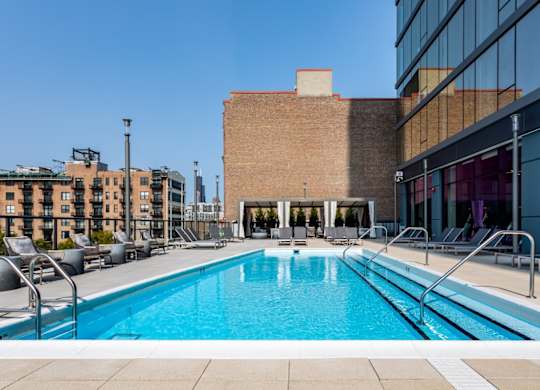 A large swimming pool in front of a building with a glass facade.
