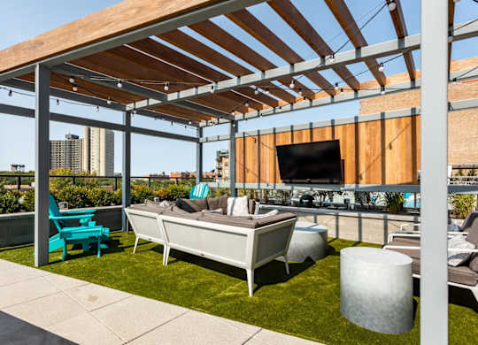 A patio with a white couch and a television on the wall.
