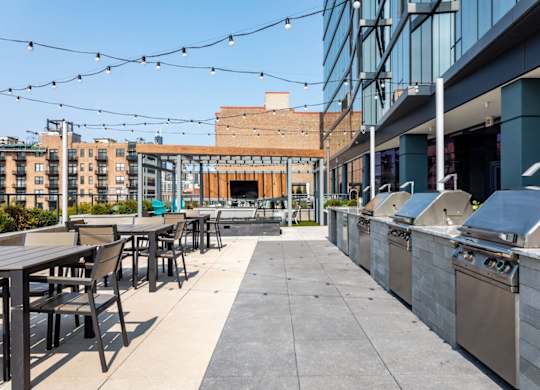 A patio with tables and chairs is surrounded by buildings.