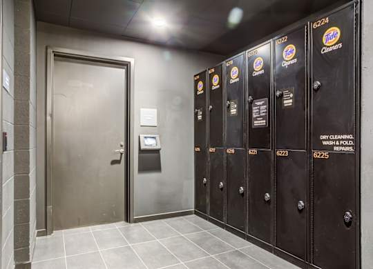 A row of Tide laundry detergent vending machines are lined up in a hallway.