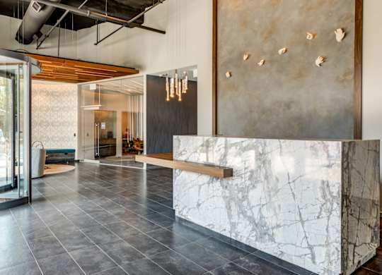 A reception area with a marble counter and a wall with a metal plate.