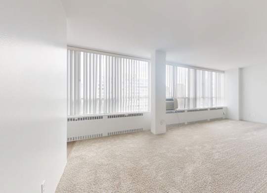 A white room with a carpet floor and a radiator.