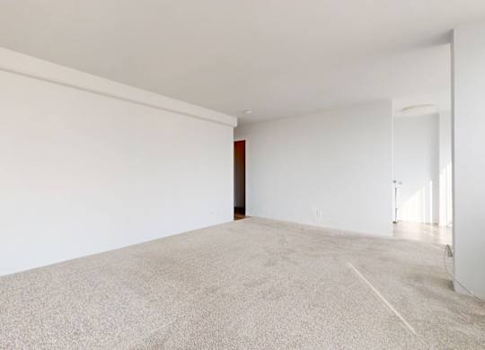 A large, empty room with a carpeted floor and white walls.