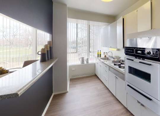 A modern kitchen with white appliances and wooden floors.