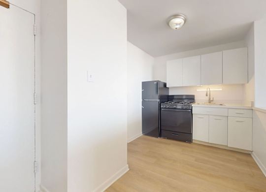 A kitchen with a black fridge and white cabinets.