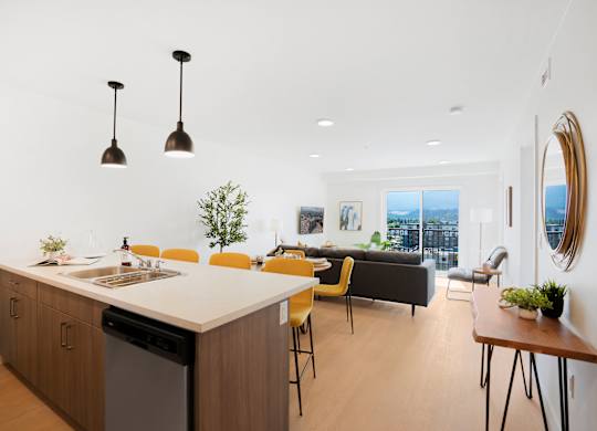 A modern kitchen with a large island and yellow chairs.