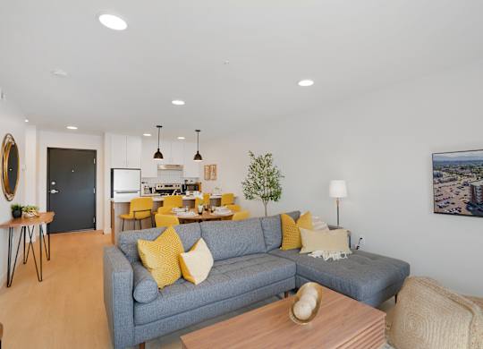 A living room with a grey couch and yellow pillows.