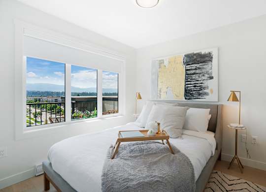 A bedroom with a large bed, a lamp, and a painting on the wall.