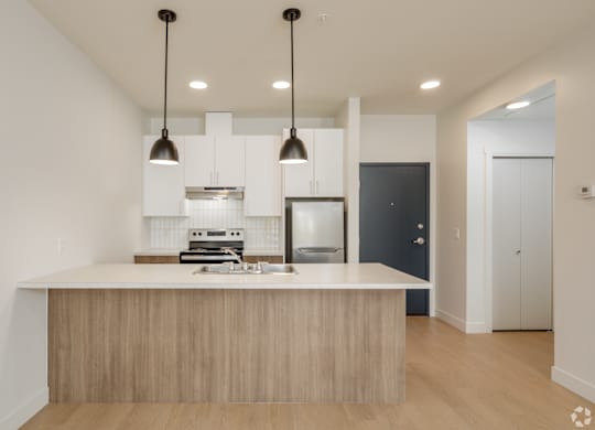 A modern kitchen with a wooden island and pendant lights.