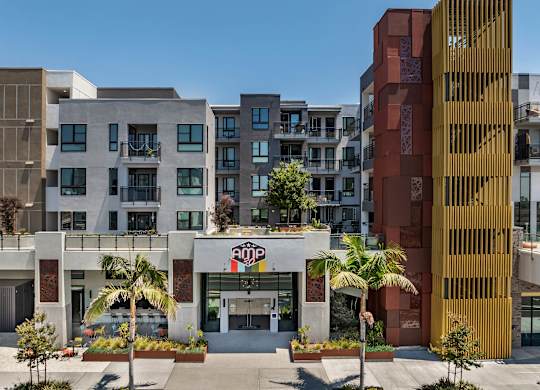 Modern apartment building entrance with landscaping at AMP 30 Apartments, San Diego