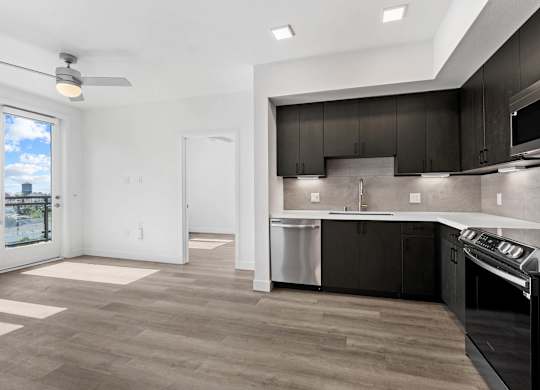 Modern kitchen with dark cabinetry and stainless appliances at AMP 30 Apartments, San Diego
