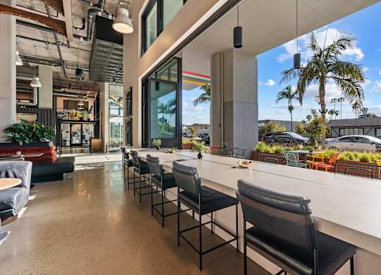 Indoor outdoor workspace with bar seating and palm trees at AMP 30 Apartments, San Diego, CA 92116